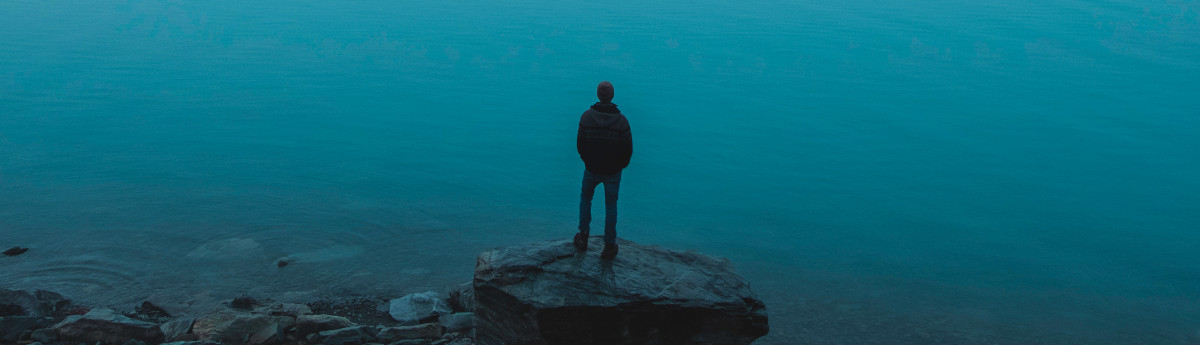 man standing on a rock near water